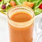 Copycat state fare lemon vinaigrette salad dressing in a jar and a salad behind it.