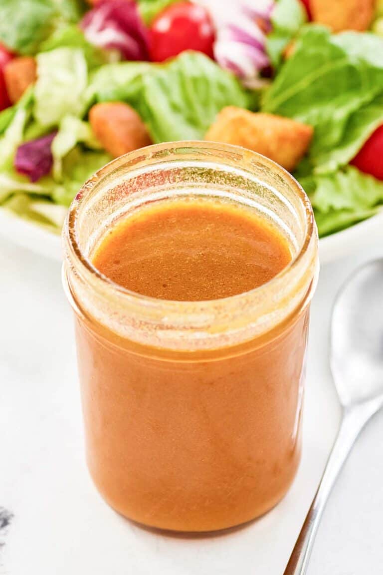 Copycat state fare lemon vinaigrette salad dressing in a jar and a salad behind it.