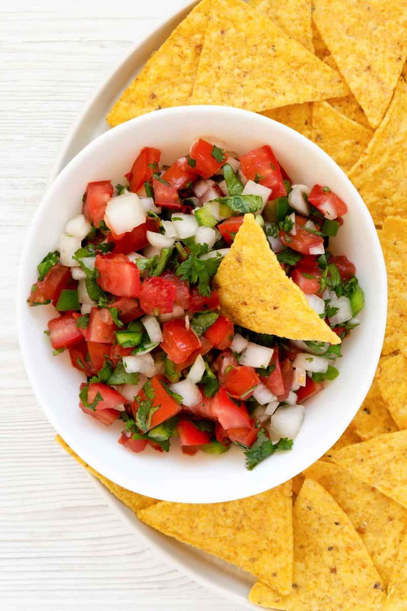 Copycat TGI Friday's pico de gallo in a bowl on a plate with tortilla chips.