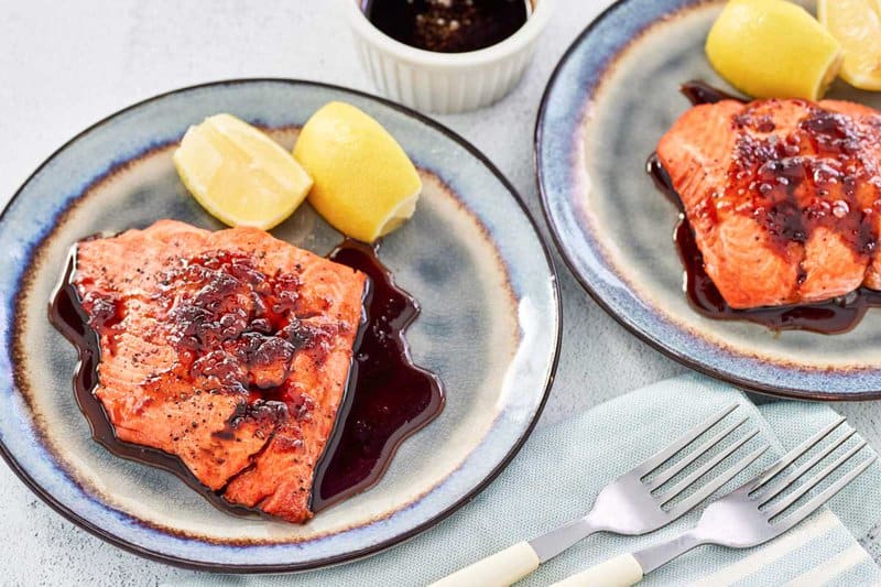 Copycat Cheddar's bourbon glazed salmon on two plates and two forks beside them.