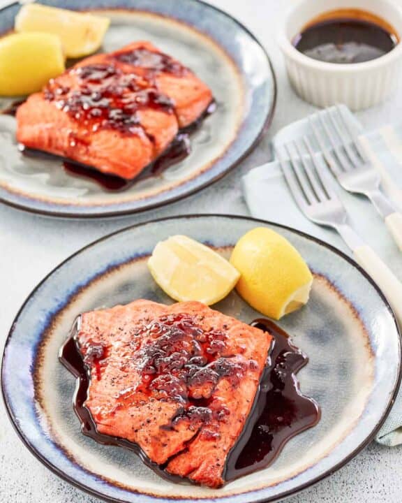 Copycat Cheddar's bourbon glazed salmon and lemon wedges on two plates.