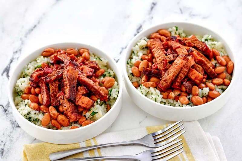 Homemade Chipotle smoked brisket over beans and rice in two bowls.