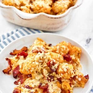 Copycat Domino's cheddar bacon loaded tots on a plate and in a serving dish.