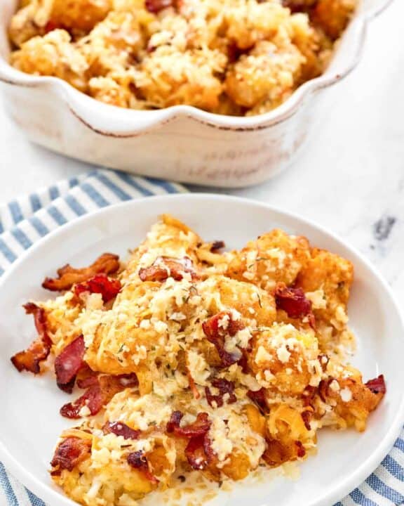 Copycat Domino's cheddar bacon loaded tots on a plate and in a serving dish.