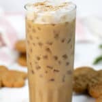 Copycat Starbucks gingerbread oat milk chai latte in a tall glass and cookies behind it.