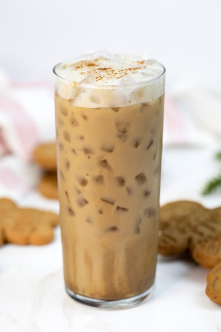 Copycat Starbucks gingerbread oat milk chai latte in a tall glass and cookies behind it.