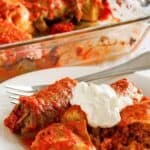 Stuffed cabbage rolls on a plate and in a baking dish behind it.