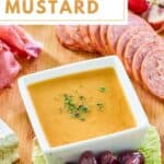 A small bowl of homemade sweet hot mustard on a charcuterie board.