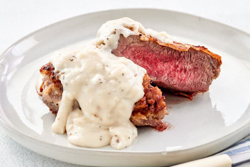 Copycat Texas Roadhouse chicken fried sirloin steak topped with gravy on a plate.