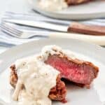 Copycat Texas Roadhouse chicken fried sirloin and gravy on two plates.