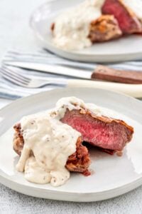 Copycat Texas Roadhouse chicken fried sirloin and gravy on two plates.