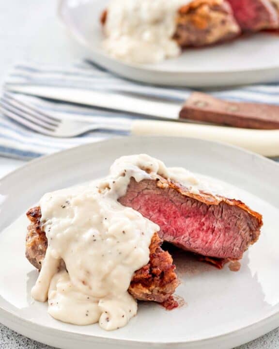 Copycat Texas Roadhouse chicken fried sirloin and gravy on two plates.