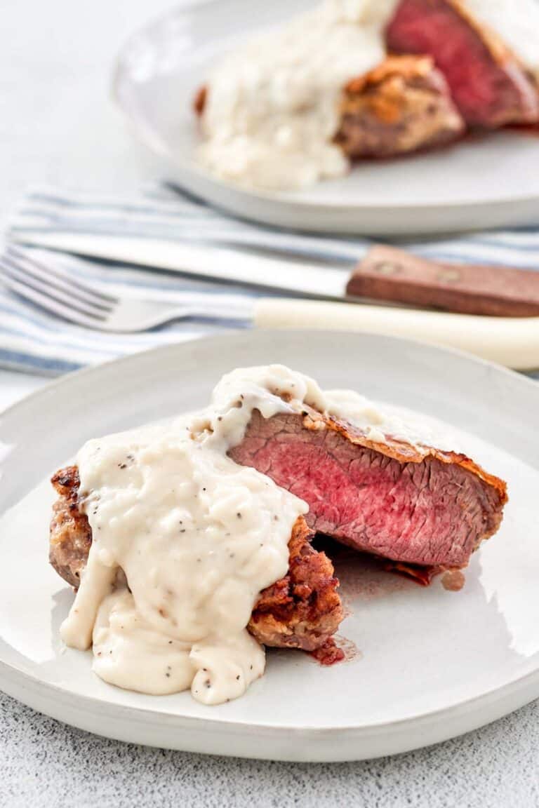 Copycat Texas Roadhouse chicken fried sirloin and gravy on two plates.