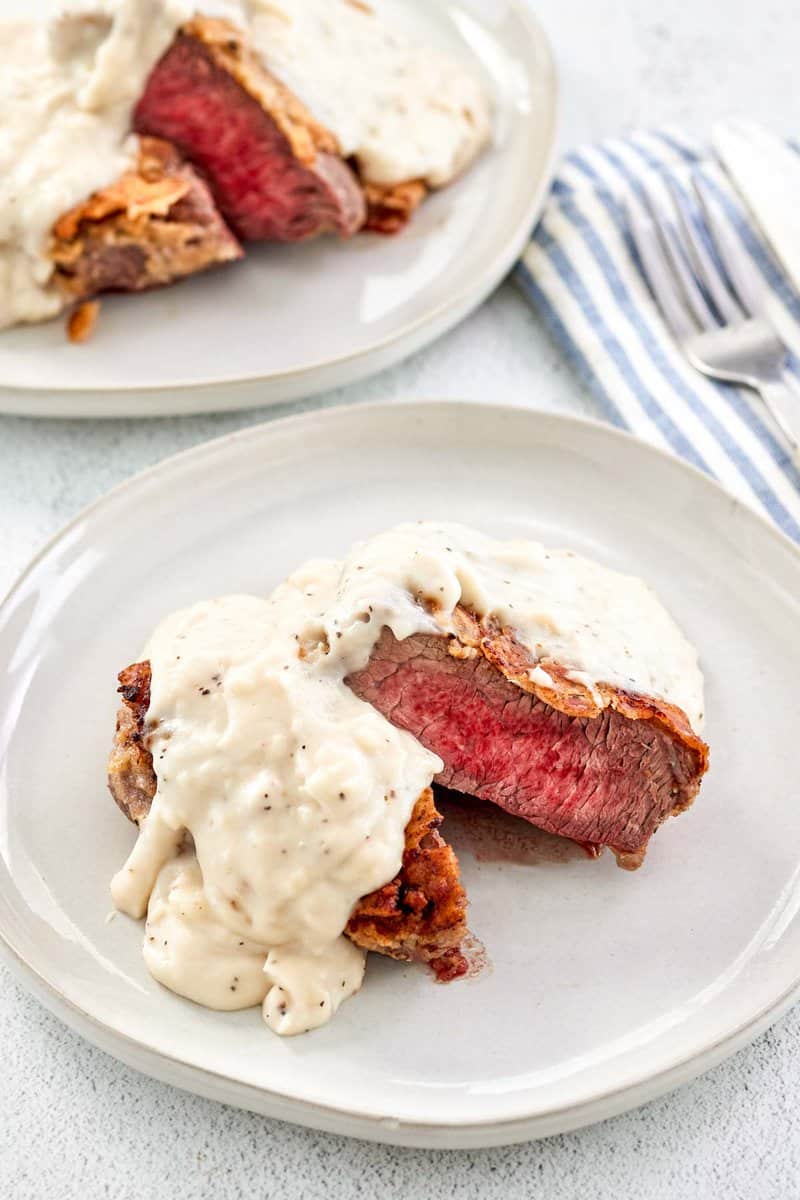 Copycat Texas Roadhouse chicken fried sirloin steak and gravy on two plates.