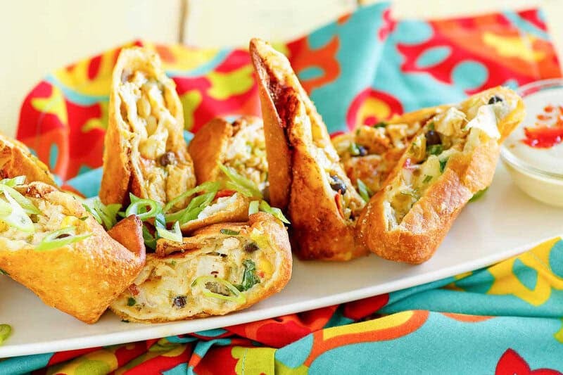 Copycat Chili's southwest egg rolls and a cup of avocado ranch dressing on a platter.