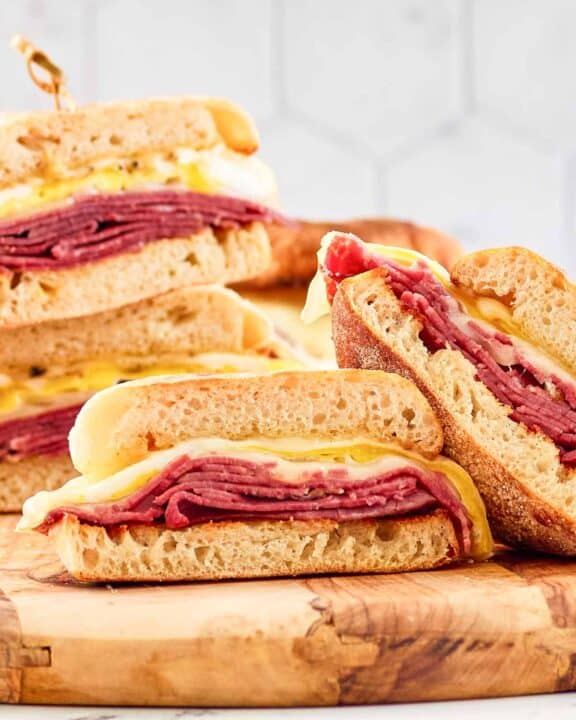 Homemade corned beef breakfast sandwiches cut in half and on a wood board.