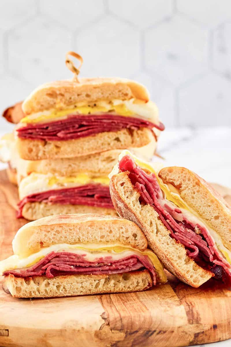 Homemade corned beef breakfast sandwiches on a wood serving board.