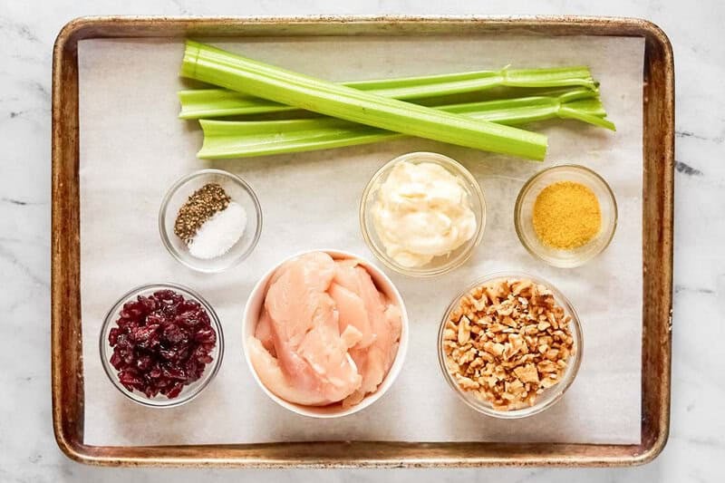 Chicken salad with cranberries and walnuts ingredients on a tray.