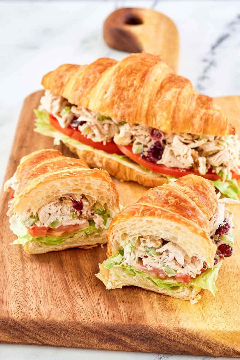 Chicken salad with cranberries and walnuts sandwiches on a wood board.