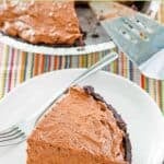 A slice of homemade chocolate pudding pie on a plate and a pie server behind it.