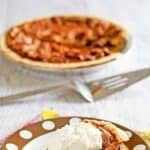 A slice of homemade Cracker Barrel chocolate pecan pie on a plate and the pie behind it.