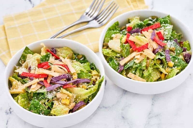 Copycat Houston's southwest caesar salad in two bowls and two forks on cloth napkins.