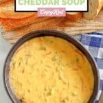 A bowl of homemade Panera broccoli cheddar soup and bread slices on a board.