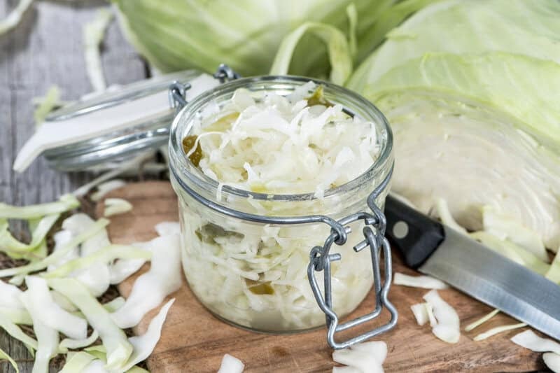 Homemade coleslaw that keeps in a jar, a knife, and fresh cabbage.