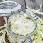 A jar of coleslaw that keeps and sliced cabbage around it.