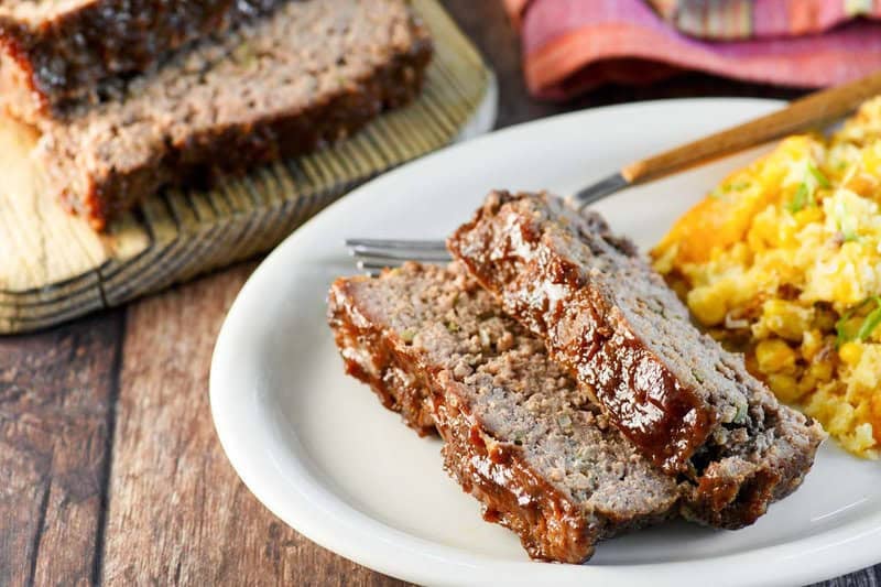 Copycat Cracker Barrel meatloaf on a plate and the meatloaf behind it.