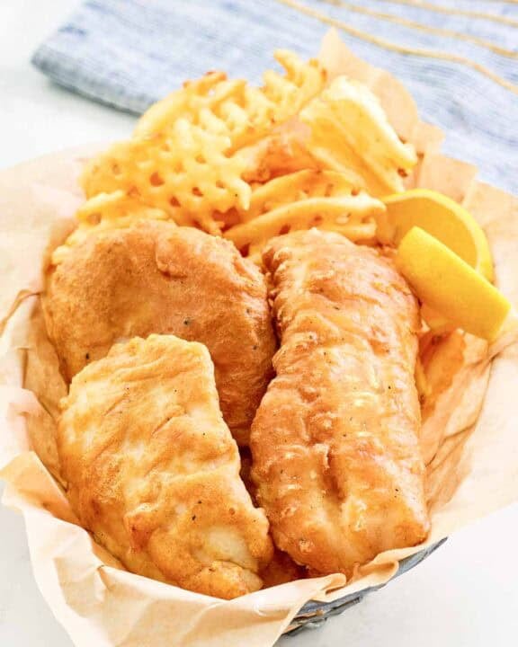 Copycat Long John Silver's batter fried fish, lemon wedges, and fries in a basket.