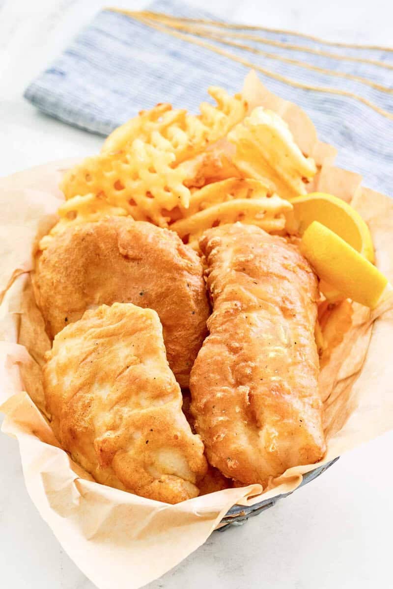 Copycat Long John Silver's batter fried fish, lemon wedges, and fries in a basket.