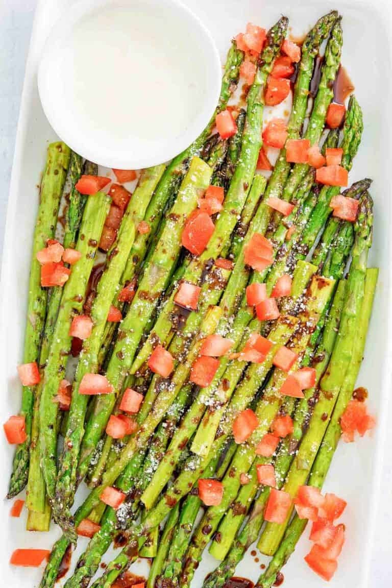Copycat olive garden parmesan roasted asparagus with dipping sauce on a platter.