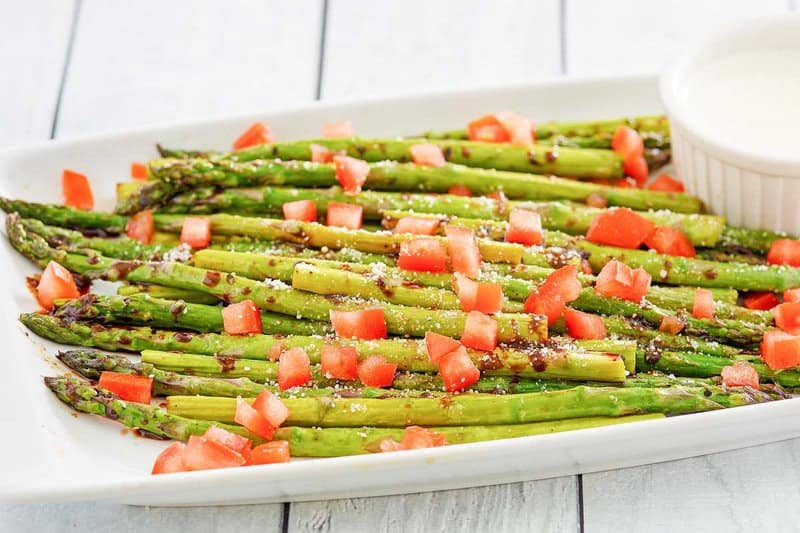 Copycat olive garden parmesan roasted asparagus topped with chopped tomatoes.