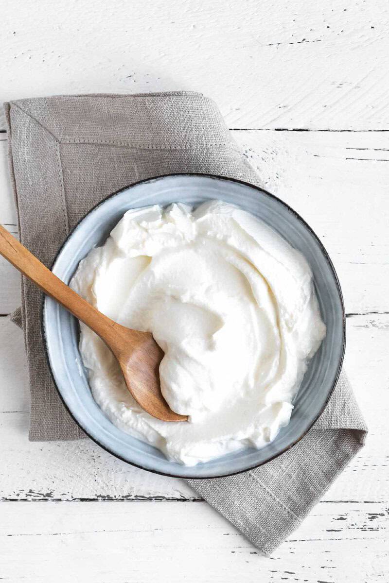 Sweetened vanilla yogurt in a bowl on a wood surface.