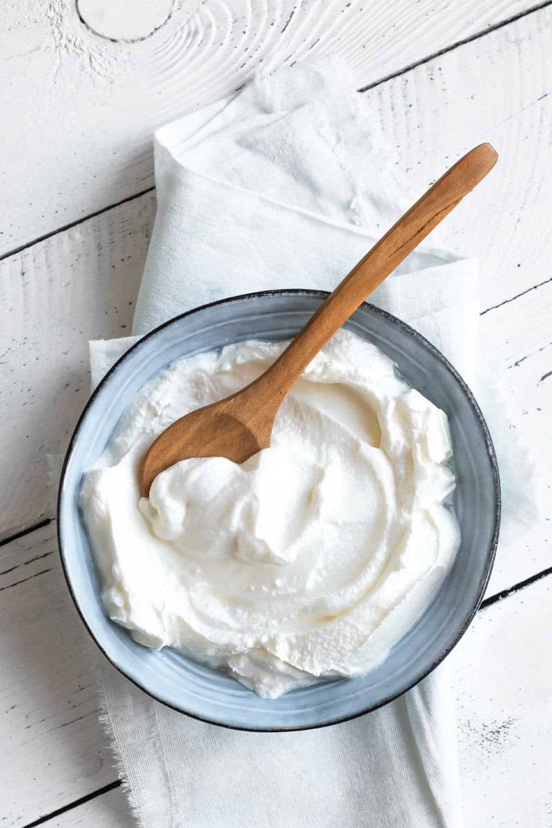 Sweetened yogurt in a bowl on a wood surface.