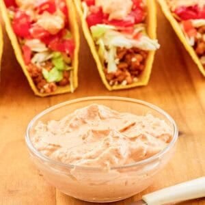 Copycat Taco Bell chipotle sauce in a small bowl, a spoon, and tacos.