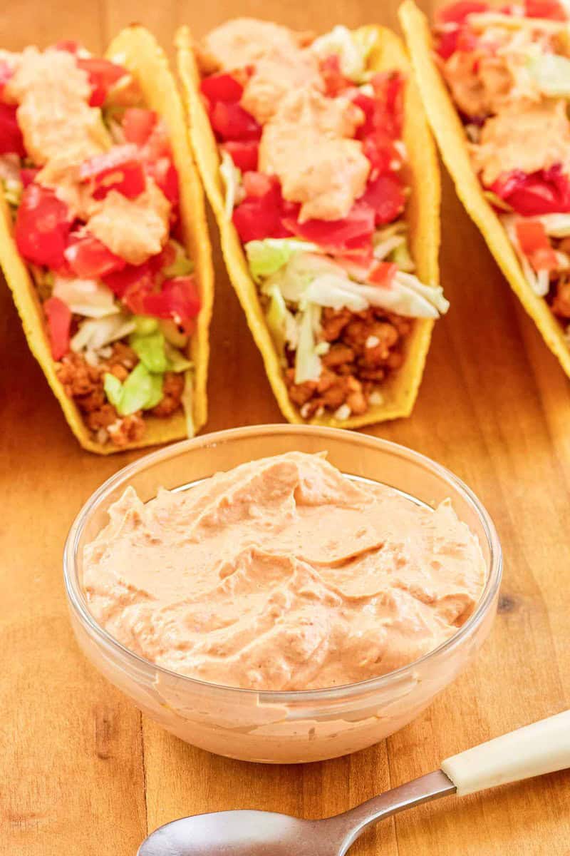 Copycat Taco Bell chipotle sauce in a bowl and tacos behind it.