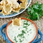 Homemade white queso dip and a plate of tortilla chips.