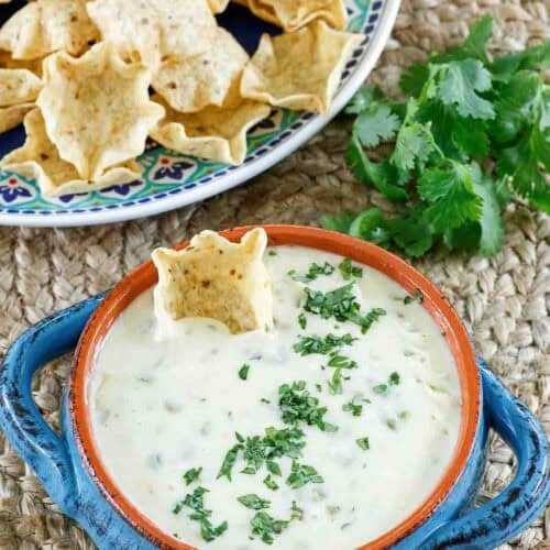 Homemade white queso dip and a plate of tortilla chips.