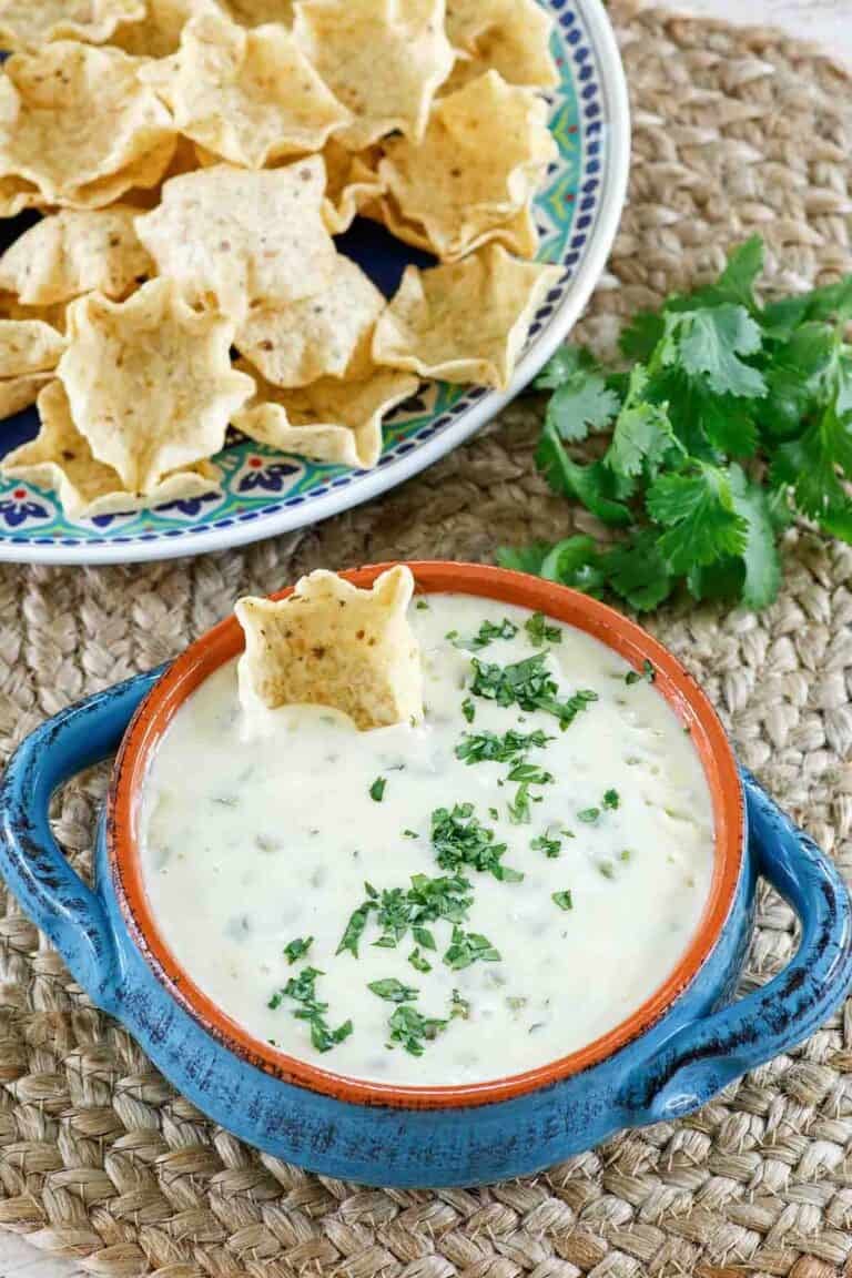 Homemade white queso dip and a plate of tortilla chips.