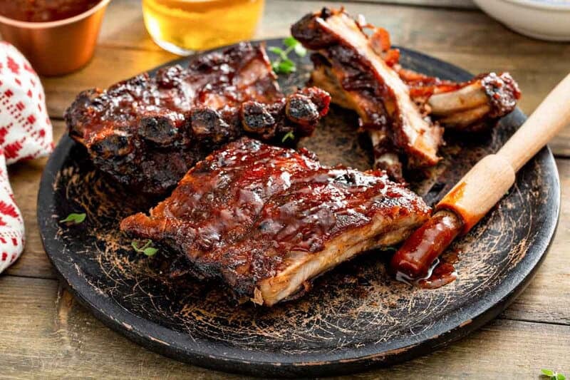 Copycat Claim Jumper bbq baby back ribs and a bbq basting brush on a plate.