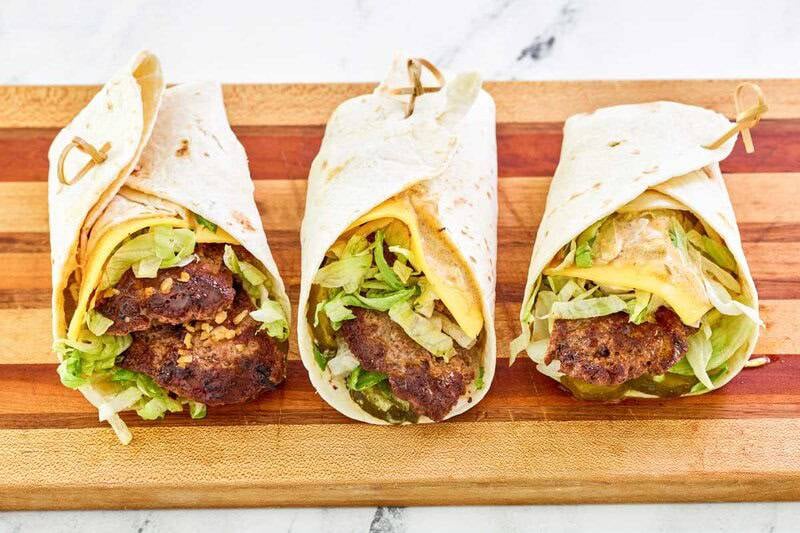 Three copycat McDonald's big mac wraps on a wood cutting board.
