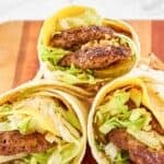 Three homemade McDonald's big mac wraps on a wood cutting board.