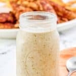 Homemade Popeyes blackened ranch sauce in a jar and a spoon next to it.