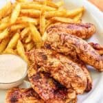 Copycat Popeyes blackened chicken tenders served with fries and dipping sauce.