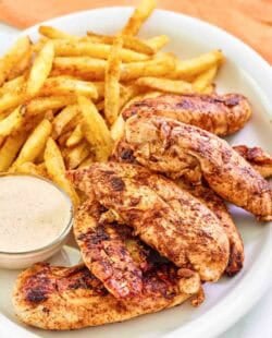 Copycat Popeyes blackened chicken tenders served with fries and dipping sauce.