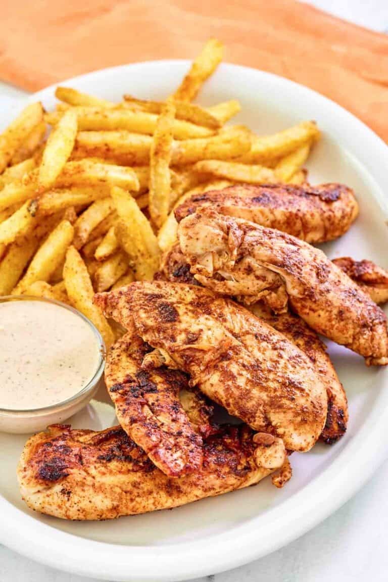 Copycat Popeyes blackened chicken tenders served with fries and dipping sauce.