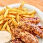 Homemade Popeyes blackened tenders and fries on a plate.
