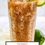Homemade sonic dirty diet coke in a glass and a lime behind it.